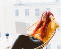 Digital nomad concept. Girl freelancer remotely working on laptop in cafe, coworking. Woman with long pink dreadlocks in informal Royalty Free Stock Photo