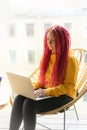 Digital nomad concept. Girl freelancer remotely working on laptop in cafe, coworking. Woman with long pink dreadlocks in informal Royalty Free Stock Photo