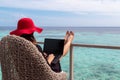 Young woman with red hat working on a computer in a tropical destination