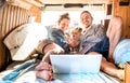 Digital nomad couple with cute dog using laptop on retro mini van transport - Travel life inspiration concept with indie people Royalty Free Stock Photo