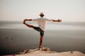 A digital nomad, a man in a hat, a businessman does yoga on the rocks by the sea at sunset time, does a business