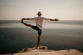 A digital nomad, a man in a hat, a businessman does yoga on the rocks by the sea at sunset time, does a business