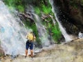 Digital painting of a man standing and looking at waterfall