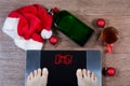 Digital scales with female feet on them and sign omg! surrounded by Christmas decorations, bottle and glass of alcohol. Royalty Free Stock Photo