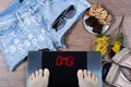 Digital scales with female feet on them and sign omg! surrounded by mimosa flowers, shorts and sweets. Royalty Free Stock Photo