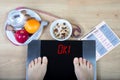 Digital scales with female feet on them surrounded by healthy food Royalty Free Stock Photo