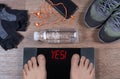 Digital scales with male feet on them and sign yes! surrounded by gymshoes, sport gloves, water Royalty Free Stock Photo