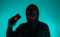 Digital security Concept. Anonymous hacker with mask holding smartphone hacked