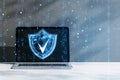 Digital shield icon on laptop screen with binary code overlay representing cybersecurity on a gray background