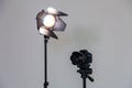 Digital SLR camera and a spotlight with a Fresnel lens on a gray background. Shooting in the interior