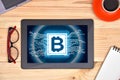 Digital tablet computer with bitcoin symbol hologram on screen Royalty Free Stock Photo