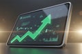 Digital tablet displaying financial growth chart with glowing arrow Royalty Free Stock Photo