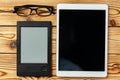 Digital tablet and electronic reader book with glasses on wooden background top view Royalty Free Stock Photo