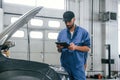 Digital tablet in hands. Auto mechanic working in garage. Repair service Royalty Free Stock Photo