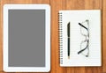 Digital tablet mock up by eyeglasse and notepad on wood deck