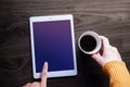 Digital Tablet Mockup Image. Screen as Clipping Path. Woman Touching on a Display while Drinking Coffee, Wooden Table, Top View Royalty Free Stock Photo