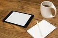 Digital tablet, notepad and coffee on table