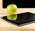Digital tablet pc and green apple in front of blackboard on wood table Royalty Free Stock Photo
