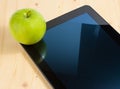 Digital tablet pc and green apple on wood table Royalty Free Stock Photo