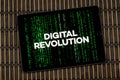 a digital tablet with the phrase digital revolution over a green digital code and a wooden background Royalty Free Stock Photo
