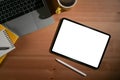 Digital tablet with white screen, laptop, coffee cup and notebook on wooden office desk. Royalty Free Stock Photo