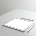 A digital tablet with a white screen is placed on a light gray desk surface. Two stylus Royalty Free Stock Photo