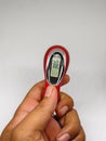Digital tasbih counter held in hand, showing a close-up of a red and silver device with an LCD screen for counting.