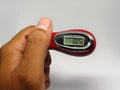 Digital tasbih counter held in hand, showing a close-up of a red and silver device with an LCD screen for counting.