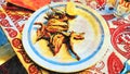 Watercolorstyle representing a plate of fried anchovies with lemon ready to serve