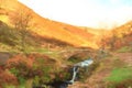 Digital watercolour of an autumnal waterfall and stone packhorse bridge at Three Shires Head in the Peak District. Royalty Free Stock Photo