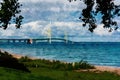 Digitally created watercolor painting of the Mackinaw Bridge on a summertime day framed by trees and the shorelinte Royalty Free Stock Photo