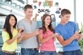 Digitally generated image of friends using smart phone with various icons flying agiant building Royalty Free Stock Photo