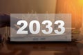2033 digits on the background of a person working in the evening at the computer