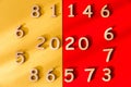 Digits 2020 on a red and yellow background in the middle of a circle of numbers. View from above. Shadow falls on the background