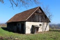 Dilapidated abandoned small old barn with wooden walls and attached leaning outdoor toilet made on cracked concrete foundation Royalty Free Stock Photo