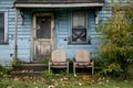 A dilapidated blue house with boarded windows and two old chairs out front, symbolizing neglect and abandonment. Concept Royalty Free Stock Photo
