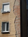 Dilapidated building facade. Cracked and pealed exterior plaster on brick wall and old window frames, no people Royalty Free Stock Photo