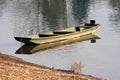 Dilapidated old light green wooden river boat made from wooden boards left next to dry grass covered river bank Royalty Free Stock Photo