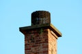 Dilapidated old red building brick chimney with plants growing from cracks and concrete top covered with dense rusted wire mesh Royalty Free Stock Photo