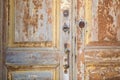 The dilapidated part of the entrance door with the remains of brown paint with a handle and locks as a symbol of the abandoned lif