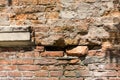 Dilapidated with potholes old brick wall of the building, made of red brick, close up. Background or texture Royalty Free Stock Photo