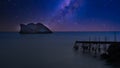 Dilapidated, rundown pier with island in the background on starry night