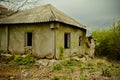 Dilapidated Rural Cottage on a Cloudy Day With Overgrown Vegetation. Abandoned house falling apart with nature taking Royalty Free Stock Photo