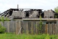 Dilapidated rural house after the fire stands behind the fence Royalty Free Stock Photo