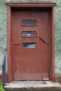 Dilapidated shabby brown wooden door on the green wall of an old house Royalty Free Stock Photo