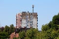 Dilapidated small apartment building with cracked falling facade and dense cell phone antennas and transmitters on top