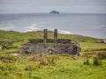 Dilapidated stone building in Irish countryside region with Skelig Michael Island