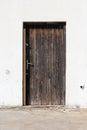Dilapidated wooden doors with faded color in need of restoration locked with padlock and mounted on white wall with cracked facade Royalty Free Stock Photo
