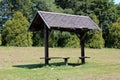 Dilapidated wooden public bench with makeshift roof covered with broken roof tiles at local public park Royalty Free Stock Photo