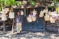 Local elderly native East Timorese woman, street vending traditional wicker baskets hanging on ropes, near Dili, Timor-Leste.